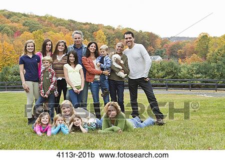 Stock Image - Portrait of families with children and dog on field. Fotosearch