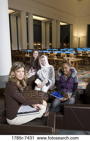 Stock Image - Portrait of four women students in a sitting lounge in a library. Fotosearch