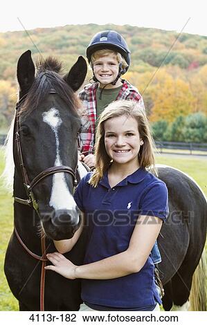 Portrait of girl assisting boy horseback riding View Large Photo Image Stock Image - Portrait of girl assisting boy horseback riding. Fotosearch