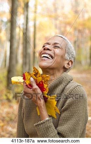 Portrait of mature woman holding Autumn leaves and laughing View Large Photo Image Stock Image - Portrait of mature woman holding Autumn leaves and laughing. Fotosearch