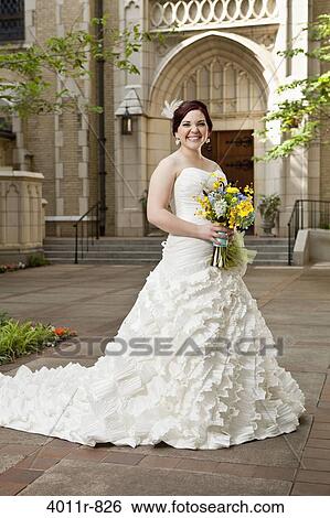 Portrait of smiling bride standing in front of church courtyard View Large Photo Image Stock Photograph - Portrait of smiling bride standing in front of church courtyard. Fotosearch