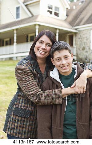 Portrait of smiling mother and son standing in front of large house View Large Photo Image Stock Photo - Portrait of smiling mother and son standing in front of large house. Fotosearch