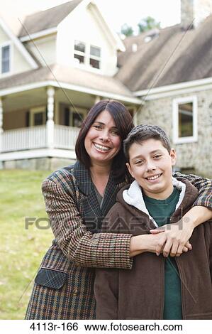 Portrait of smiling mother and son standing in front of large house View Large Photo Image Stock Photograph - Portrait of smiling mother and son standing in front of large house. Fotosearch