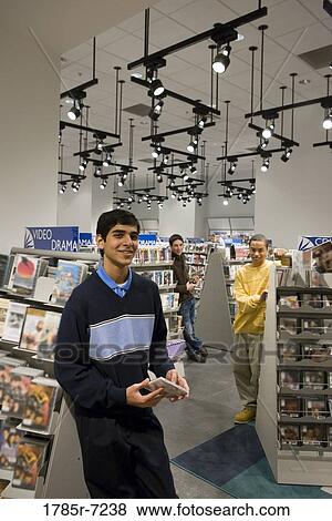 Portrait of smiling teenage boys standing amidst shelves of DVDs View Large Photo Image Stock Photo - Portrait of smiling teenage boys standing amidst shelves of DVDs. Fotosearch