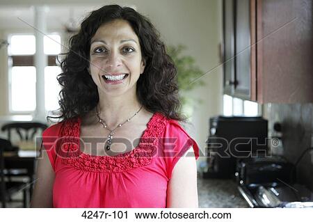 Stock Image - Portrait of smiling woman in kitchen. Fotosearch