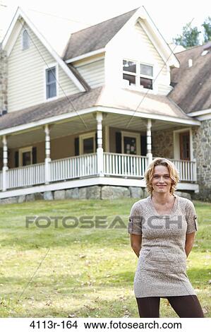 Portrait of smiling woman standing in front of large house View Large Photo Image Picture - Portrait of smiling woman standing in front of large house. Fotosearch