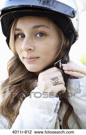 Stock Image - Portrait of teenage girl fastening helmet. Fotosearch