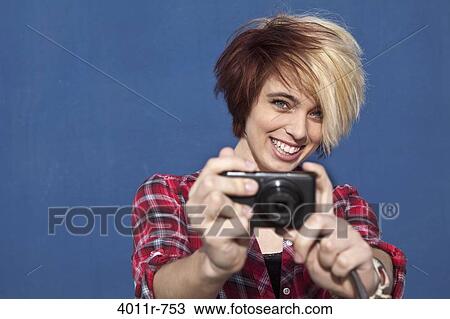 Stock Image - Portrait of teenage girl using digital camera. Fotosearch