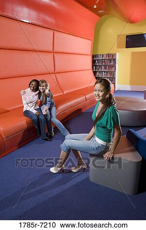 Portrait of teenage girlfriends sitting in the library View Large Photo Image Stock Image - Portrait of teenage girlfriends sitting in the library. Fotosearch