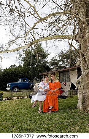 Portrait of Tex-Mex mother and daughter sitting on swing in front yard of house View Large Photo Image Stock Photo - Portrait of Tex-Mex mother and daughter sitting on swing in front yard of house. Fotosearch