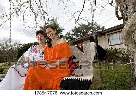 Portrait of Tex-Mex mother and daughter sitting on swing in front yard of house View Large Photo Image Stock Photograph - Portrait of Tex-Mex mother and daughter sitting on swing in front yard of house. Fotosearch