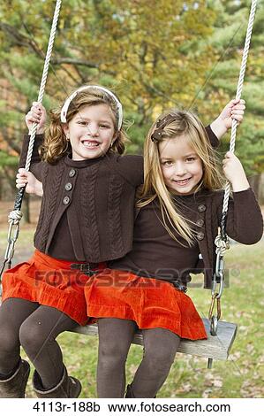 Stock Image - Portrait of two girls on swing. Fotosearch