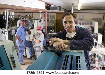 Portrait of two men and a woman in coveralls next to some machinery View Large Photo Image Stock Image - Portrait of two men and a woman in coveralls next to some machinery. Fotosearch