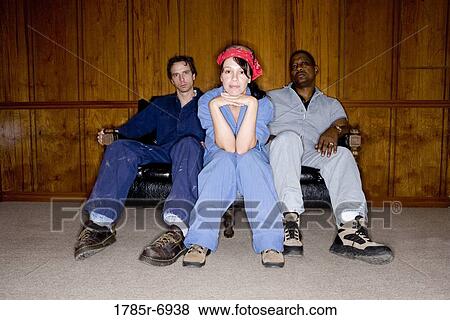 Portrait of two men and a woman in coveralls sitting on a sofa View Large Photo Image Stock Photo - Portrait of two men and a woman in coveralls sitting on a sofa. Fotosearch