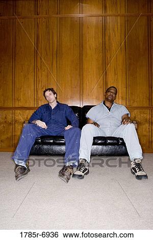 Portrait of two men in coveralls sitting on a sofa View Large Photo Image Stock Photograph - Portrait of two men in coveralls sitting on a sofa. Fotosearch
