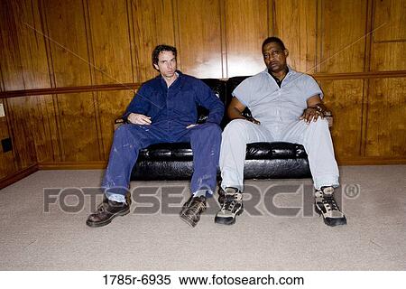 Portrait of two men in coveralls sitting on a sofa View Large Photo Image Stock Photography - Portrait of two men in coveralls sitting on a sofa. Fotosearch