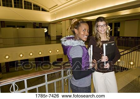 Portrait of two women students standing in the lobby of a building View Large Photo Image Stock Photograph - Portrait of two women students standing in the lobby of a building. Fotosearch