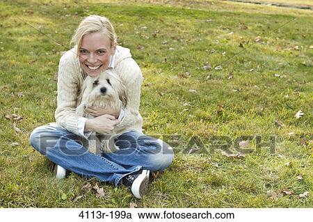 Portrait of woman with white dog sitting on field View Large Photo Image Stock Image - Portrait of woman with white dog sitting on field. Fotosearch