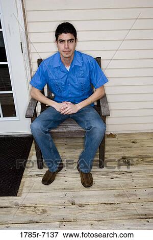 Portrait of young man sitting on armchair View Large Photo Image Stock Photo - Portrait of young man sitting on armchair. Fotosearch
