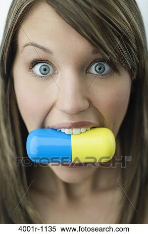 Portrait of young woman biting large capsule pill View Large Photo Image Stock Photography - Portrait of young woman biting large capsule pill. Fotosearch
