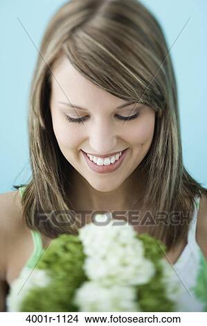 Portrait of young woman smelling flowers View Large Photo Image Picture - Portrait of young woman smelling flowers. Fotosearch