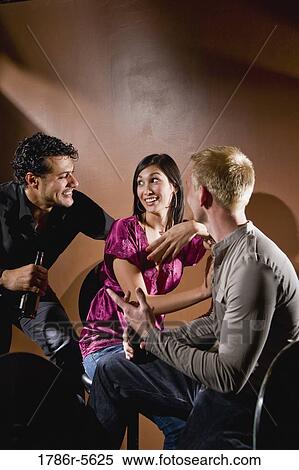 Stock Photography - Pretty young woman chatting with two men. Fotosearch