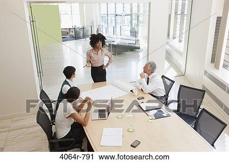 Stock Image - Project discussions amongst employees in boardroom. Fotosearch