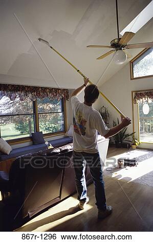 Rear view of a man painting a wall with a paint roller View Large Photo Image Stock Photograph - Rear view of a man painting a wall with a paint roller. Fotosearch
