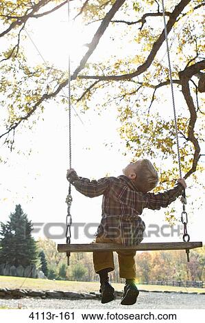 Rear view of boy on swing View Large Photo Image Stock Image - Rear view of boy on swing. Fotosearch