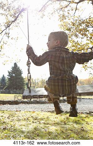 Rear view of boy on swing View Large Photo Image Stock Image - Rear view of boy on swing. Fotosearch