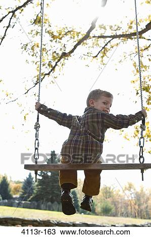 Stock Image - Rear view of boy on swing. Fotosearch