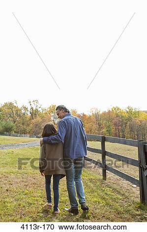 Rear view of father and daughter walking on field View Large Photo Image Stock Image - Rear view of father and daughter walking on field. Fotosearch