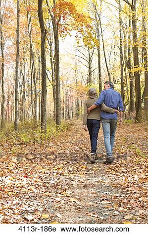 Rear view of mature couple walking on Autumn forest track View Large Photo Image Stock Image - Rear view of mature couple walking on Autumn forest track. Fotosearch