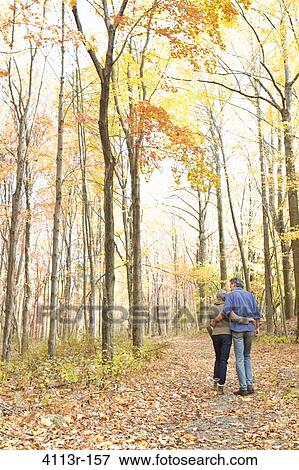 Rear view of mature couple walking on Autumn forest track View Large Photo Image Stock Photo - Rear view of mature couple walking on Autumn forest track. Fotosearch
