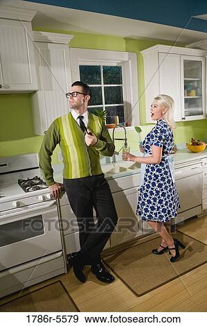 Stock Photo - Retro couple at home in kitchen chatting. Fotosearch