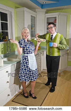 Stock Photograph - Retro couple at home in kitchen eating cookies. Fotosearch