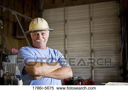 Senior man in warehouse wearing hard hat View Large Photo Image Stock Photography - Senior man in warehouse wearing hard hat. Fotosearch