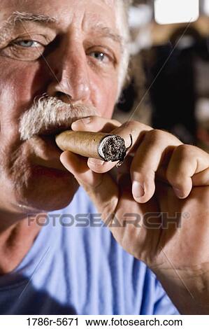 Stock Image - Senior man smoking cigar. Fotosearch