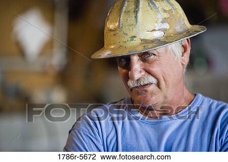 Senior worker standing in workshop with hardhat View Large Photo Image Stock Image - Senior worker standing in workshop with hardhat. Fotosearch
