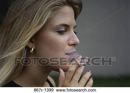 Stock Photo - Side profile of a young woman smoking a cigarette. Fotosearch