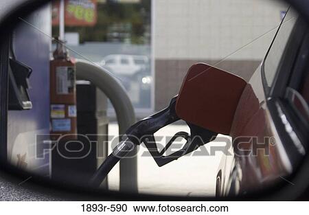 side rear view mirror shot of a gasoline pump nozzle inserted in a fuel tank entry on a red automobile View Large Photo Image Stock Image - side rear view mirror shot of a gasoline pump nozzle inserted in a fuel tank entry on a red automobile. Fotosearch