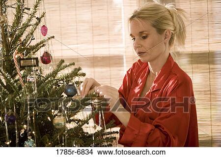 Side view of a woman decorating Christmas tree View Large Photo Image Picture - Side view of a woman decorating Christmas tree. Fotosearch