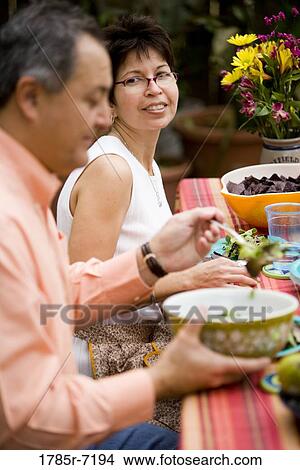 Side view of mature couple having a meal at a picnic table View Large Photo Image Picture - Side view of mature couple having a meal at a picnic table. Fotosearch
