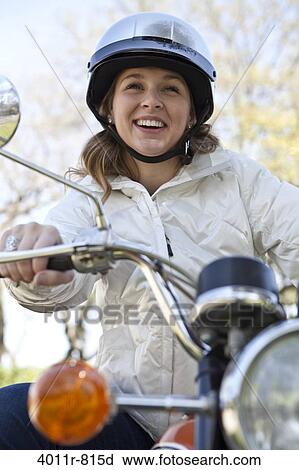 Stock Image - Smiling teenage girl sitting on motorcycle. Fotosearch