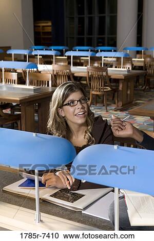 Stock Image - Student sitting in the reading room of a library. Fotosearch