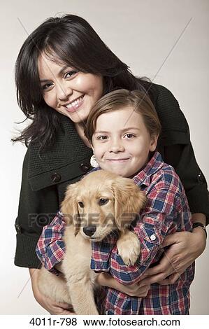 Studio portrait of woman with son holding puppy View Large Photo Image Stock Photo - Studio portrait of woman with son holding puppy. Fotosearch