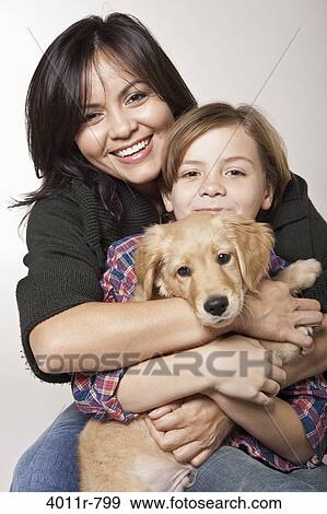Stock Photo - Studio portrait of woman with son holding puppy. Fotosearch