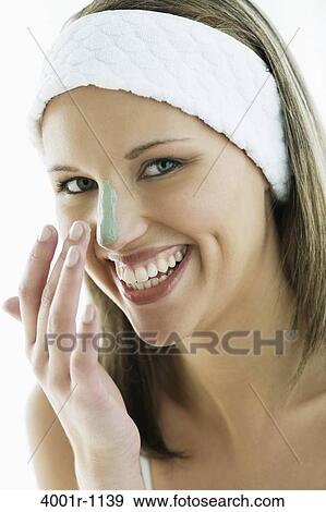 Stock Photo - Studio portrait of young woman with cream on nose, smiling. Fotosearch