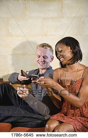 Stock Photography - Stylish young interracial couple texting. Fotosearch