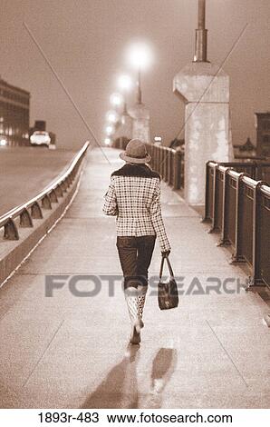 Stylish young woman walking on a bridge at night in a city View Large Photo Image Stock Image - Stylish young woman walking on a bridge at night in a city. Fotosearch